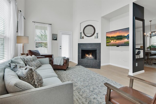 1356 Portsmouth Dr, Providence Village, TX 76227 - living area with a chandelier, a tiled fireplace, wood finished floors, a towering ceiling, and baseboards