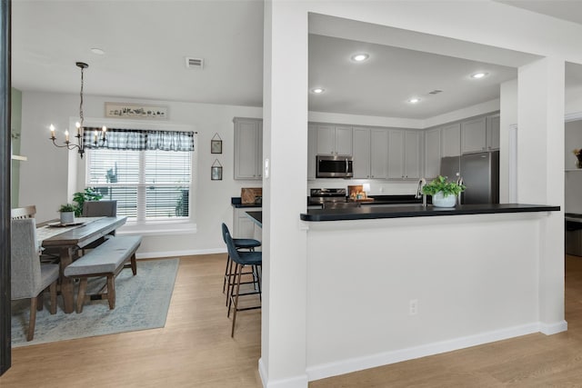 1356 Portsmouth Dr, Providence Village, TX 76227 - kitchen with appliances with stainless steel finishes, gray cabinetry, a chandelier, light wood-type flooring, and recessed lighting