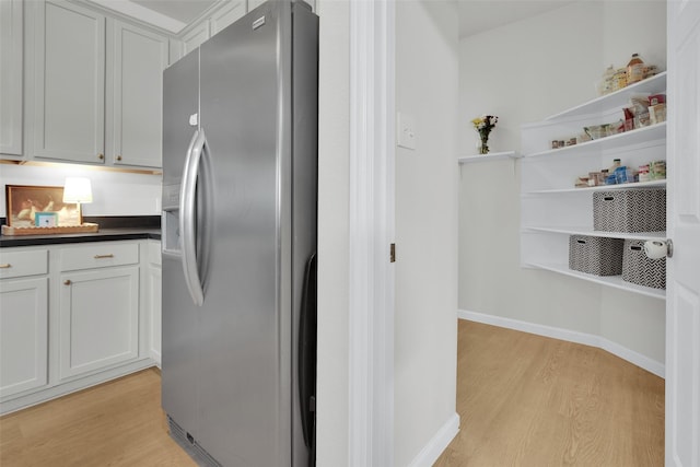 1356 Portsmouth Dr, Providence Village, TX 76227 - kitchen with stainless steel fridge with ice dispenser, light wood-style floors, dark countertops, open shelves, and baseboards