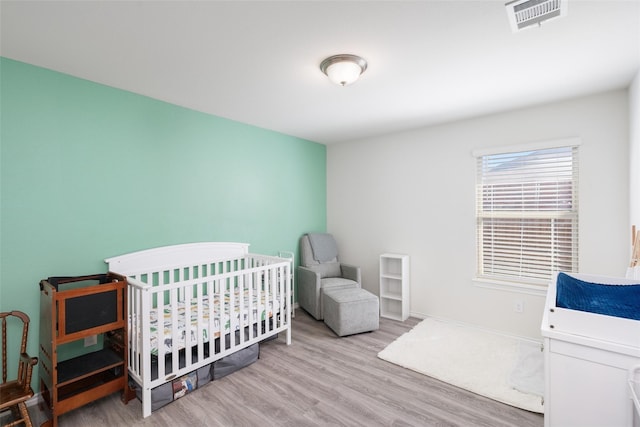 100 Samuel St, Denton, TX 76207 - bedroom with wood finished floors, baseboards, and a crib