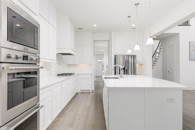 2130 Lassen Dr, Prosper, TX 75078 - kitchen featuring appliances with stainless steel finishes, a sink, light wood-style floors, light countertops, and a kitchen island with sink