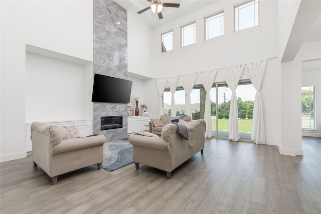 2130 Lassen Dr, Prosper, TX 75078 - living area with a towering ceiling, a high end fireplace, light wood-style floors, a ceiling fan, and baseboards