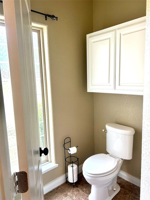 2663 Rodeo Dr, Quinlan, TX 75474 - bathroom with tile patterned flooring, toilet, healthy amount of natural light, and baseboards