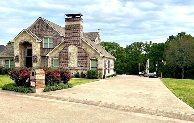 2663 Rodeo Dr, Quinlan, TX 75474 - view of front of property with stone siding, a chimney, a front lawn, and concrete driveway