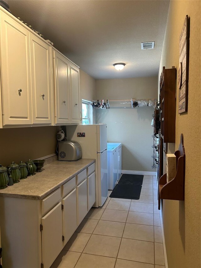 2663 Rodeo Dr, Quinlan, TX 75474 - laundry room featuring washer and dryer, cabinet space, and light tile patterned flooring