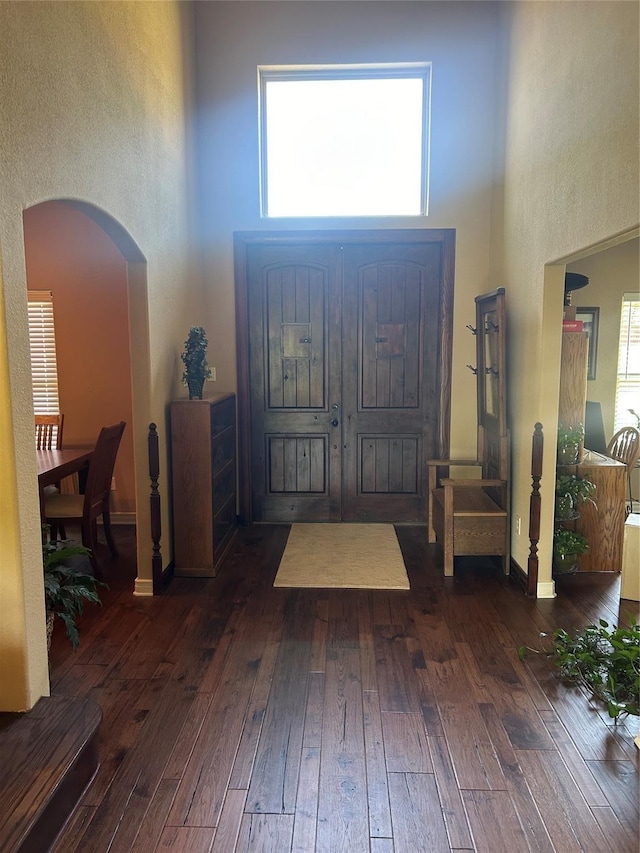 2663 Rodeo Dr, Quinlan, TX 75474 - foyer entrance featuring a high ceiling, arched walkways, dark wood-style flooring, and baseboards