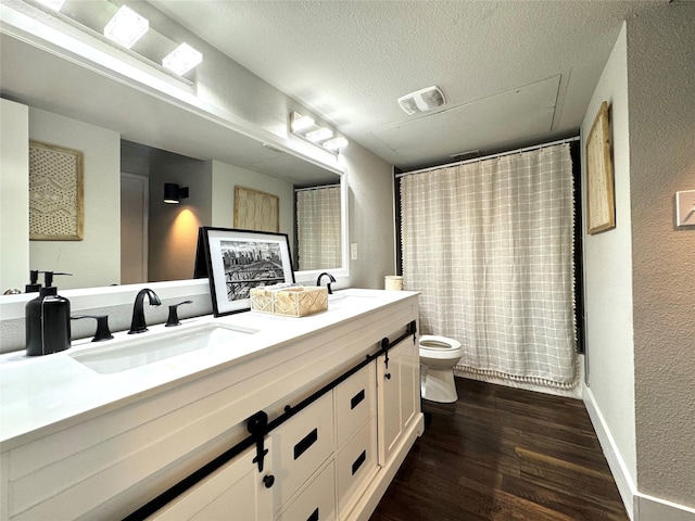 6014 Mcafee Dr, The Colony, TX 75056 - bathroom with toilet, double vanity, wood finished floors, a textured wall, and a textured ceiling