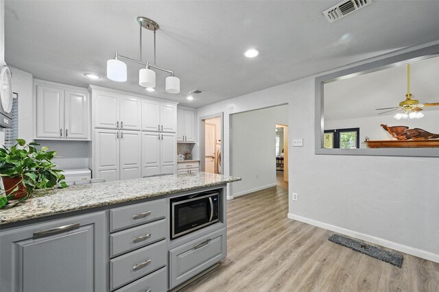 685 Cardinal Ridge Rd, Burleson, TX 76028 - kitchen with stainless steel microwave, white cabinetry, baseboards, light wood-type flooring, and recessed lighting