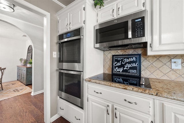 815 N Spikes Rd, Corsicana, TX 75110 - kitchen with appliances with stainless steel finishes, arched walkways, white cabinets, decorative backsplash, and ornamental molding
