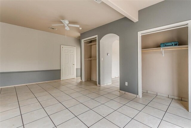 802 S Rusk St, Weatherford, TX 76086 - unfurnished bedroom featuring arched walkways, light tile patterned floors, beamed ceiling, a ceiling fan, and baseboards