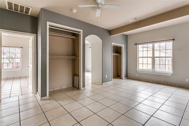 802 S Rusk St, Weatherford, TX 76086 - unfurnished bedroom with arched walkways, light tile patterned floors, and multiple windows