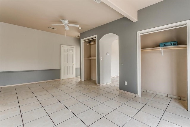 802 S Rusk St, Weatherford, TX 76086 - unfurnished bedroom featuring arched walkways, light tile patterned floors, beam ceiling, ceiling fan, and a closet