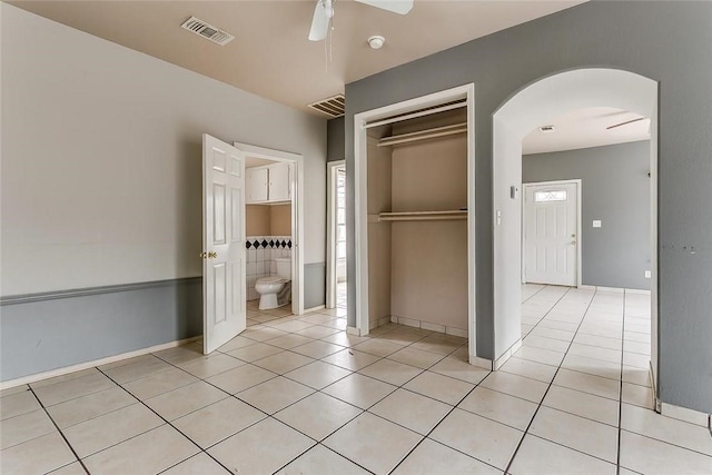 802 S Rusk St, Weatherford, TX 76086 - unfurnished bedroom with arched walkways, light tile patterned flooring, a closet, ensuite bathroom, and a ceiling fan