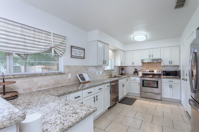 502 E Alexander Ln, Euless, TX 76040 - kitchen featuring appliances with stainless steel finishes, under cabinet range hood, backsplash, and white cabinetry