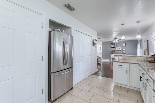 502 E Alexander Ln, Euless, TX 76040 - kitchen featuring freestanding refrigerator, white cabinets, light tile patterned floors, hanging light fixtures, and light stone countertops