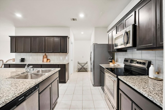 812 Draper Dr, Fate, TX 75189 - kitchen with stainless steel appliances, a sink, tasteful backsplash, light tile patterned flooring, and dark brown cabinetry