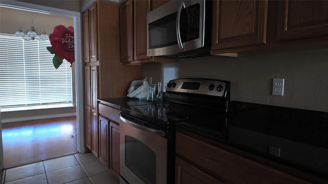 2405 Northlake Ct, Irving, TX 75038 - kitchen with appliances with stainless steel finishes, a chandelier, dark countertops, and light tile patterned flooring