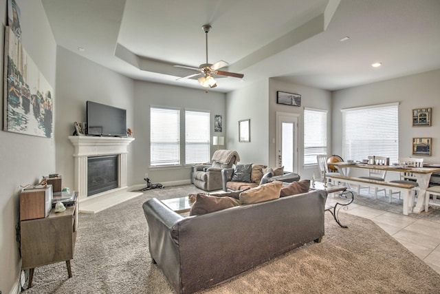 3713 Blessington Dr, Frisco, TX 75036 - tiled living area with a tray ceiling, a ceiling fan, a glass covered fireplace, recessed lighting, and baseboards