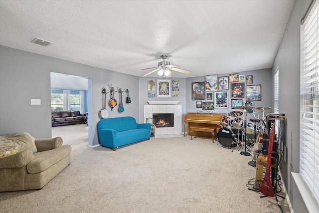 521 Ryan St, Saginaw, TX 76179 - carpeted living room with a tile fireplace, ceiling fan, and a textured ceiling