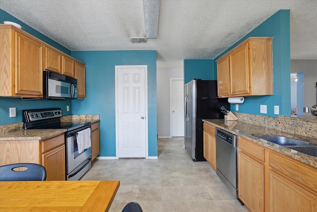 521 Ryan St, Saginaw, TX 76179 - kitchen featuring stainless steel appliances, a textured ceiling, light stone counters, and baseboards
