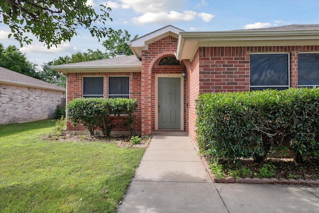 521 Ryan St, Saginaw, TX 76179 - view of exterior entry featuring brick siding, a lawn, and a shingled roof