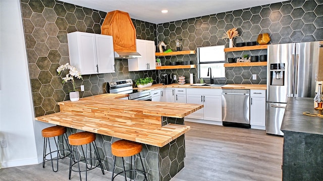 209 N Broad St, Saint Jo, TX 76265 - kitchen featuring butcher block counters, appliances with stainless steel finishes, open shelves, a sink, and ventilation hood