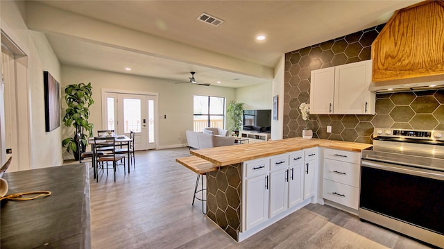 209 N Broad St, Saint Jo, TX 76265 - kitchen featuring butcher block countertops, electric range, exhaust hood, wood finished floors, and a peninsula