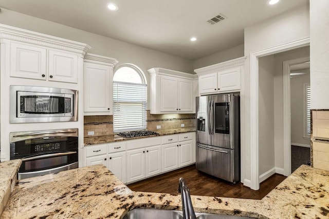 5909 Woodwind Dr, Plano, TX 75093 - kitchen featuring appliances with stainless steel finishes, light stone counters, dark wood-type flooring, white cabinets, and recessed lighting