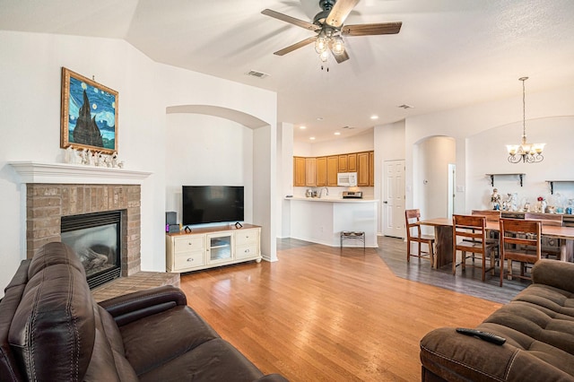 813 Royal Oak Ln, Burleson, TX 76028 - living room with arched walkways, ceiling fan, a chandelier, light wood finished floors, and a fireplace