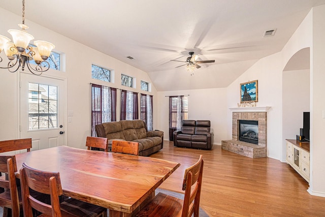 813 Royal Oak Ln, Burleson, TX 76028 - dining space with light wood-style floors, a brick fireplace, a chandelier, lofted ceiling, and ceiling fan