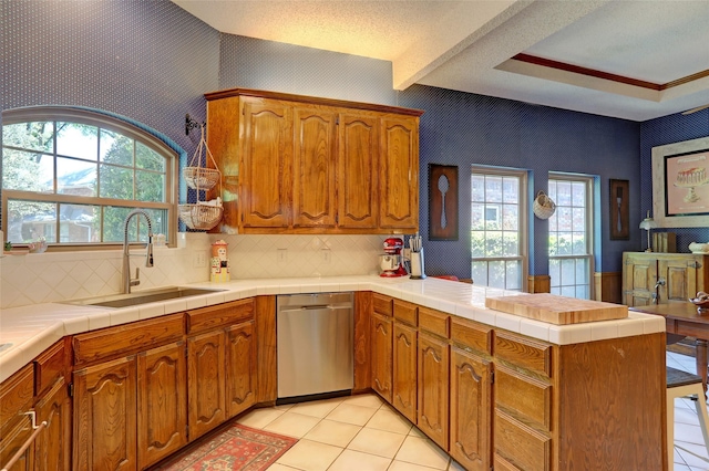3908 Jamestown Pl, Plano, TX 75023 - kitchen featuring stainless steel dishwasher, a sink, a peninsula, healthy amount of natural light, and wallpapered walls