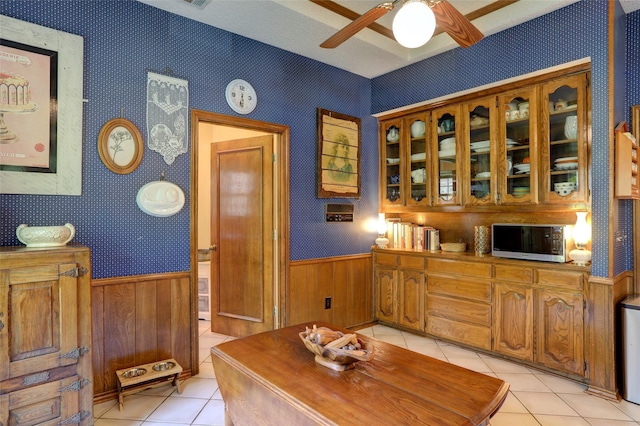 3908 Jamestown Pl, Plano, TX 75023 - home office with light tile patterned floors, a wainscoted wall, a ceiling fan, wallpapered walls, and wood walls