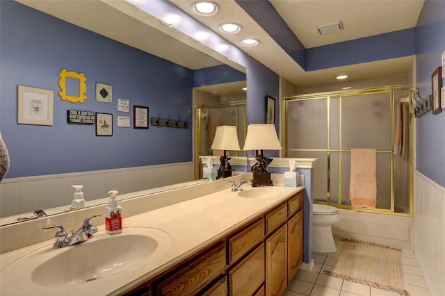 3908 Jamestown Pl, Plano, TX 75023 - bathroom featuring toilet, a wainscoted wall, tile patterned floors, double vanity, and shower / bath combination with glass door