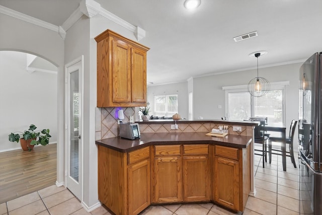 1900 Cassandra Ct, Fort Worth, TX 76131 - kitchen featuring a peninsula, freestanding refrigerator, brown cabinets, decorative backsplash, and dark countertops