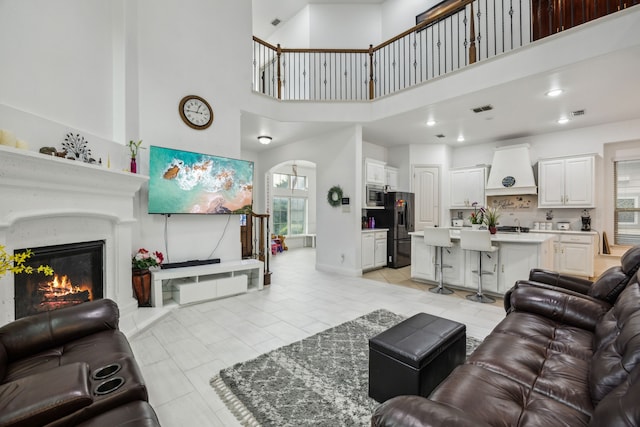 5005 Dominion Blvd, Irving, TX 75038 - living area featuring a high ceiling, light tile patterned floors, a glass covered fireplace, arched walkways, and baseboards