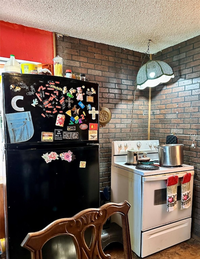 903 College St, Sulphur Springs, TX 75482 - kitchen featuring white electric stove, freestanding refrigerator, a textured ceiling, and brick wall