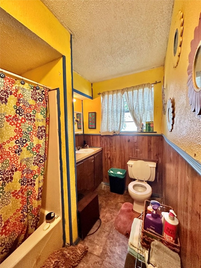 903 College St, Sulphur Springs, TX 75482 - bathroom with a textured ceiling, a wainscoted wall, vanity, wood walls, and shower / bath combo