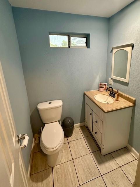 300 E Shoemaker St, Decatur, TX 76234 - bathroom with vanity, toilet, tile patterned flooring, and baseboards
