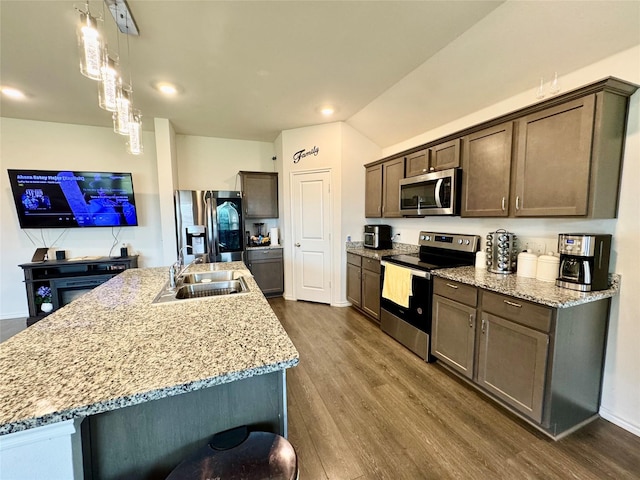 1013 Euston St, Denton, TX 76209 - kitchen with appliances with stainless steel finishes, dark brown cabinetry, dark wood-style floors, a kitchen island with sink, and light stone counters