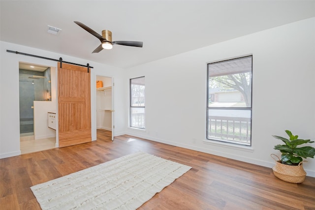 130 Holland Dr, Denison, TX 75020 - unfurnished bedroom with a barn door, multiple windows, and wood finished floors