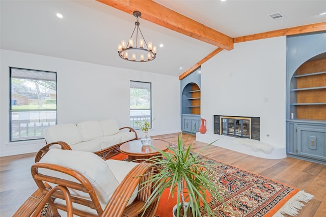 130 Holland Dr, Denison, TX 75020 - living room with built in shelves, a chandelier, a glass covered fireplace, wood finished floors, and baseboards