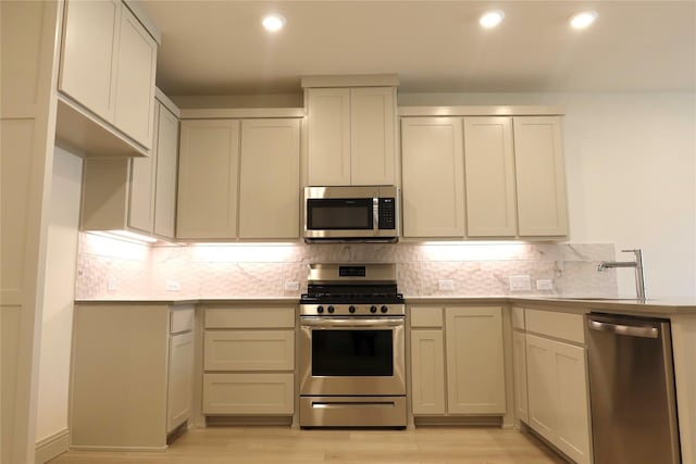 2538 Settlers Pl, Garland, TX 75042 - kitchen with appliances with stainless steel finishes, a sink, light wood-style flooring, tasteful backsplash, and light countertops