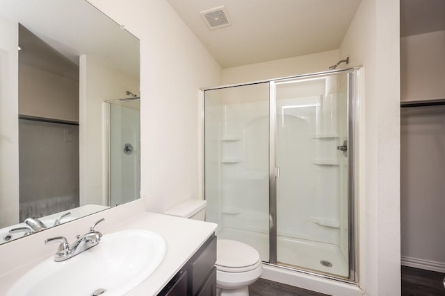 2829 Oakdale St, Dallas, TX 75215 - bathroom featuring a stall shower, toilet, vanity, a spacious closet, and wood finished floors