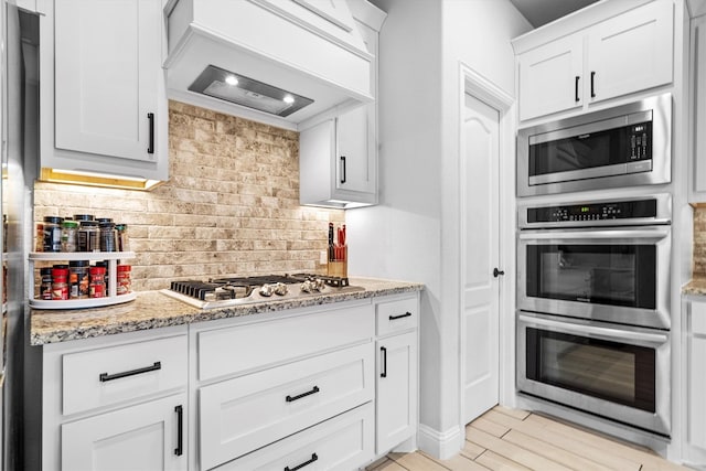 1417 Stoneleigh Pl, Aubrey, TX 76227 - kitchen featuring appliances with stainless steel finishes, custom exhaust hood, backsplash, white cabinetry, and light stone counters