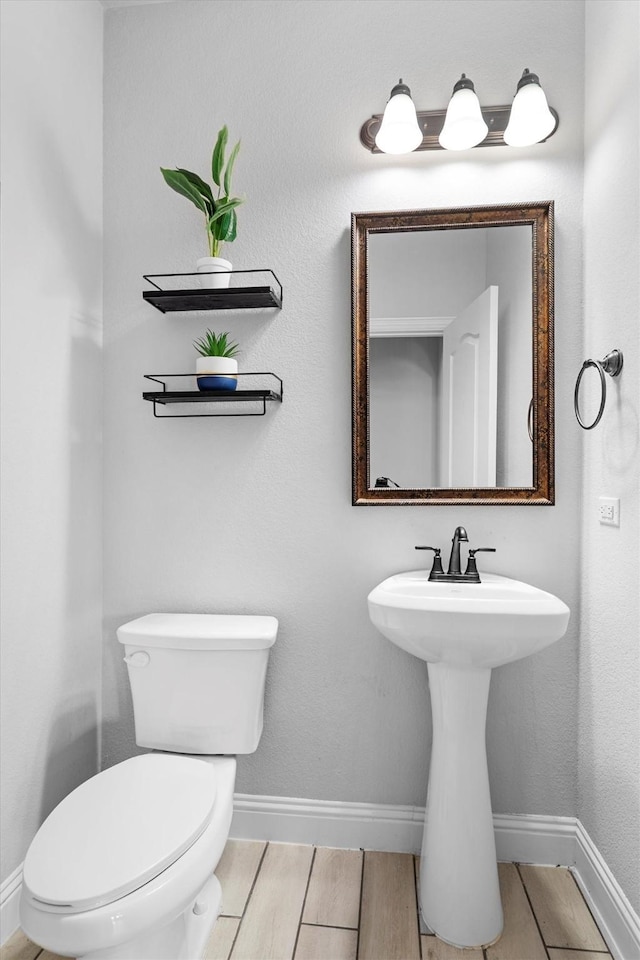 1417 Stoneleigh Pl, Aubrey, TX 76227 - half bathroom featuring toilet, baseboards, wood finished floors, and a sink