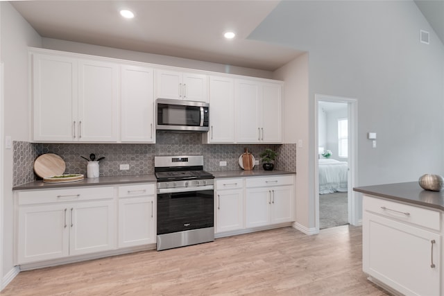 1616 Berry Ridge Trl, Aubrey, TX 76227 - kitchen featuring appliances with stainless steel finishes, white cabinetry, backsplash, dark countertops, and light wood-style flooring
