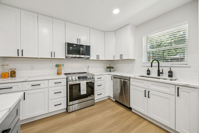 37 Devonshire Dr, Bedford, TX 76021 - kitchen featuring appliances with stainless steel finishes, light wood-type flooring, tasteful backsplash, white cabinets, and a sink