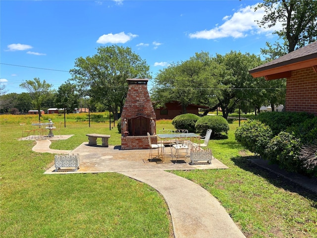 905 Bennett Dr, Bowie, TX 76230 - view of grassy yard featuring an outdoor brick fireplace and a patio area