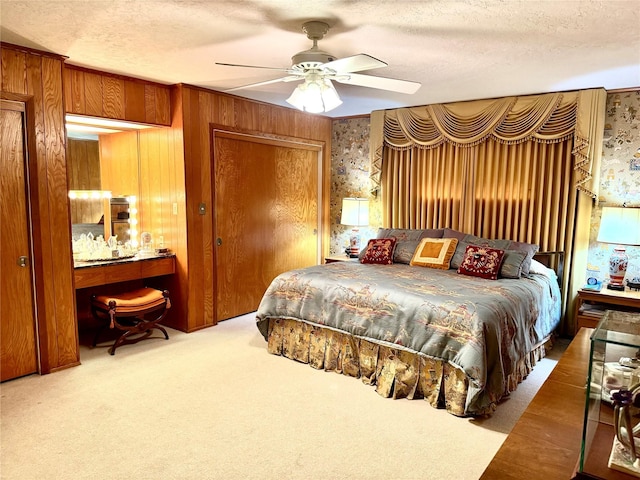 905 Bennett Dr, Bowie, TX 76230 - carpeted bedroom featuring a textured ceiling, ceiling fan, wallpapered walls, and wood walls