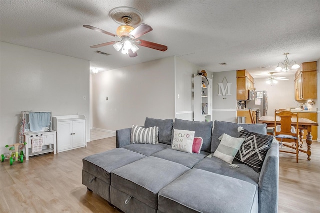 423 Parkview Dr, Burleson, TX 76028 - living area featuring a ceiling fan, a textured ceiling, light wood-style floors, a chandelier, and baseboards